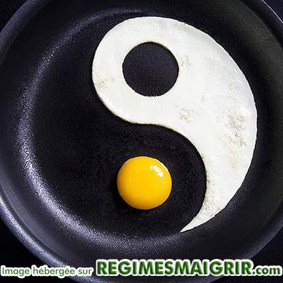Symboles du yin et du yang faits avec du blanc d'oeuf et son jaune dans une poêle