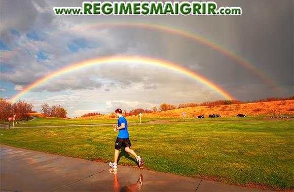 Une personne court sous un bel arc en ciel
