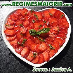 Des dizaines de fraises sont coupées et placées dans une assiette blanche en forme de coeur