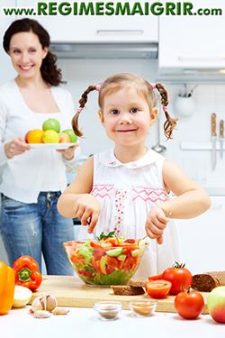 Une mère aide son enfant à apprendre les bases d'une préparation culinaire saine