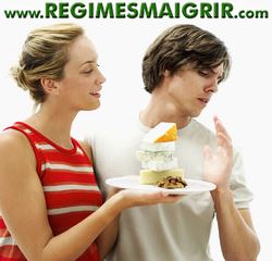Un homme repousse l'invitation d'une femme à manger un gâteau