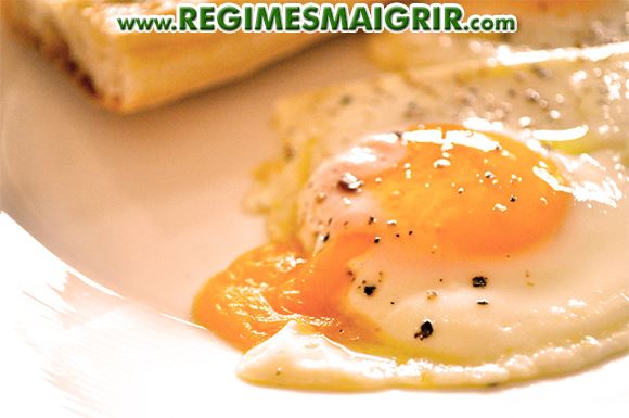 Des oeufs cuits posés dans une assiette à côté du pain