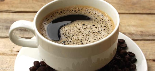 Une tasse de caf noir pose  ct des grains