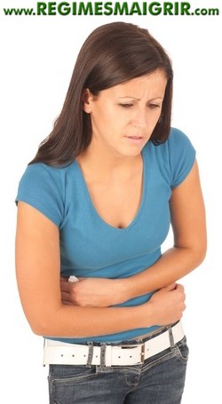 Une femme tient son ventre avec ses deux mains pour soulager des douleurs