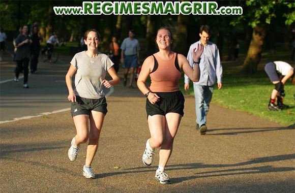 Deux femmes courent ensemble dans un parc tout en souriant