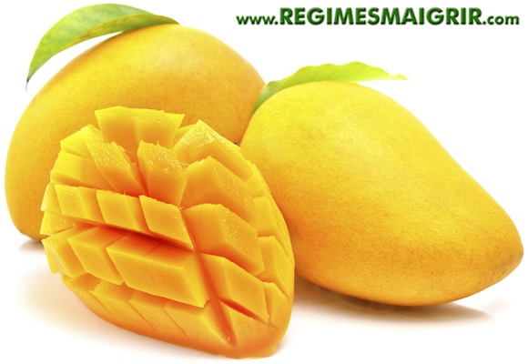 Deux mangues sont poses  ct d'une moiti de mangue coupe en cubes