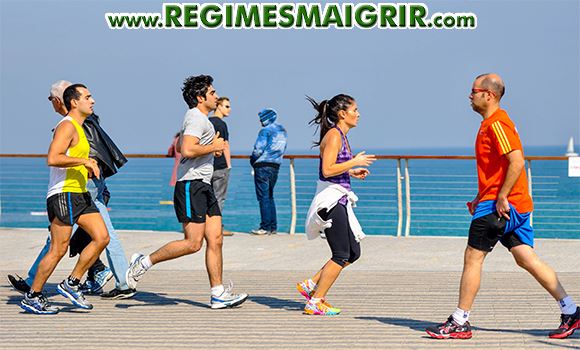 Des hommes et des femmes sont en train de faire du jogging prs d'une plage pave en bois