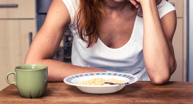 Une femme assise  table et manque d'apptit devant son assiette de nourriture