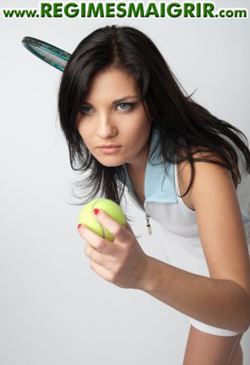 Une joueuse de tennis se prpare  servir en tenant la raquette  sa main droite et une balle jaune  sa main gauche