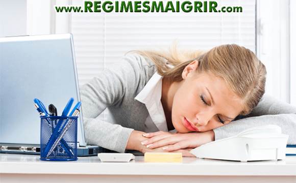 Une femme est fatigue et s'affale sur son bureau afin de se reposer