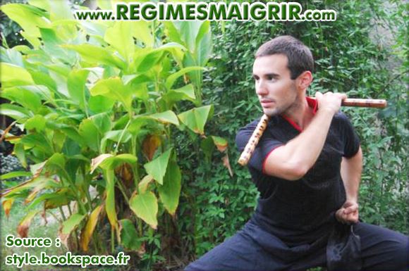 Le coach Benjamin Hennequin montre une posture de Kung-Fu en tenant un nunchaku