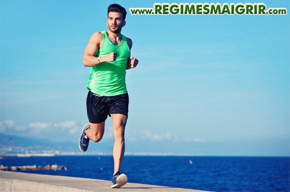 Un beau jeune homme court  ct de la plage