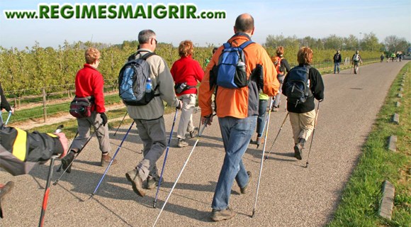 Un groupe de personnes font du nordic walking sur une route de campagne