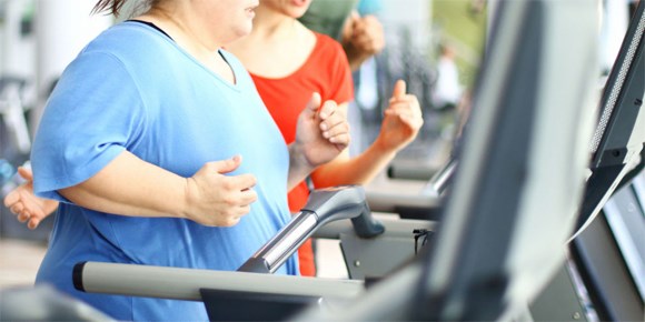 Une femme court sur un tapis roulant  ct de son instructrice de sport