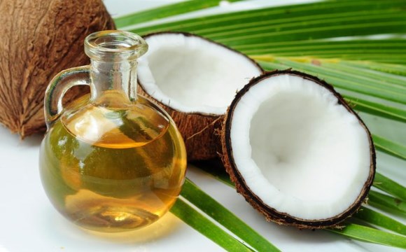 Une bouteille d'huile de noix de coco mise  ct de quelques fruits du cocotier