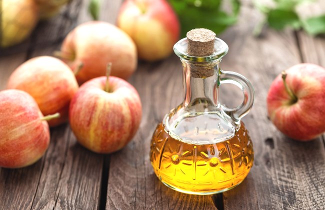 Une bouteille de vinaigre de cidre pose  ct des pommes