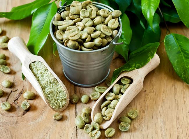 Grains de café vert dans un seau mis à côté des feuilles